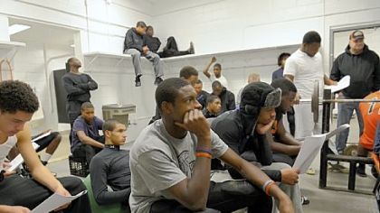 Titus Howard, center, a junior wide receiver and cornerback who has made a verbal commitment  to play football at the University of Pittsburgh, and his Bears teammates listen to defensive coach Wayne Wade during a recent strategy session in  the  team's weight room.
