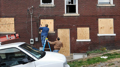 Members of the school's facilities management staff board up a home that had been converted into student apartments.