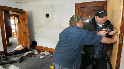 Members of the school's facilities management staff board up a home that had been converted into student apartments.