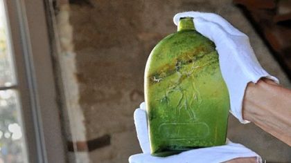Christine Davis holds up a bottle excavated at the site of The Tower at PNC Plaza at Wood and Fifth. Manufactured by Arsenal Glass Works, in what is now Lawrenceville, the bottle shows a man holding a cane. The bottle can be dated to the 1865-1869 time period.