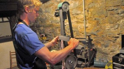 John Heidelmeier grinds an edge on a knife blank in Bar Marco's basement workshop.