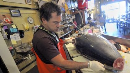 Henry Dewey, at Penn Fish Co, dismantles a large tuna in the shop.