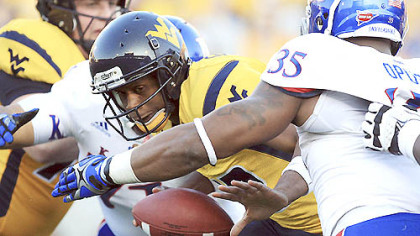 West Virginia quarterback Geno Smith is sacked by Kansas' Toben Opurum (35) and John Williams (71) during the second quarter.