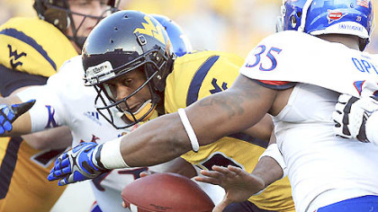 West Virginia quarterback Geno Smith is sacked by Kansas' Toben Opurum (35) and John Williams (71) during the second quarter.