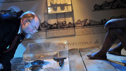Andrew Masich, president and CEO of the Heinz History Center, examines shackles, cowrie shells and a gun displayed near the entrance of the center's exhibit on slavery.