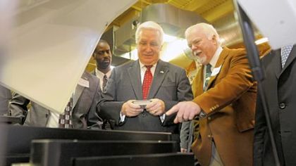 Kent Rockwell, chairman and CEO of ExOne, right, shows Gov. Tom Corbett parts manufactured by ExOne in North Huntingdon during a visit to Acutronic.