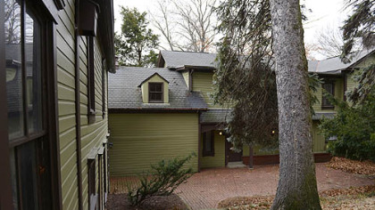 The back of the house features a red brick pation and mature trees.