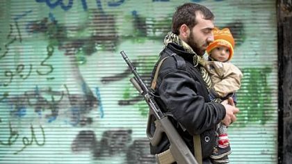 A rebel fighter carries his son after Friday prayers in al-Fardos, a neighborhood in Aleppo, Syria.
