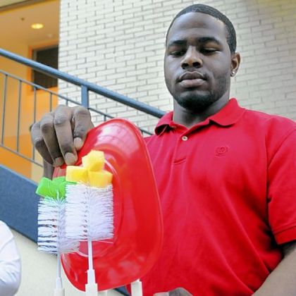 Ben Antoine demonstrates his team's Scrub Master with rotating brushes to clean dinnerware placed in a sink as Carnegie Mellon University seniors showed their Capstone Design Projects for mechanical engineering.