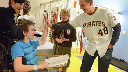 Pitcher Jared Hughes gives a high-five to Garrett Morgan, 15, of Erie, Tuesday while Stacy Eber, left, an occupational therapist at the Children's Institute of Pittsburgh, and Hughes' teammate Andrew McCutchen look on.