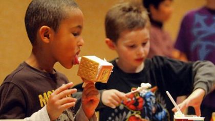 Noah McFadden, 5, tests the quality of construction supplies as he creates his gingerbread house next to Eric Wilson, 6, at a free gingerbread house workshop at the Scott Township Public Library on Sunday.