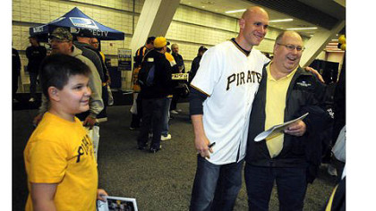 Thomas Nicely, 12, of Delmont, left, watches his father Dennis Nicely get photographed by mom Christine (not in picture) with Pirates shortstop Clint Barmes at PirateFest at David L. Lawrence Convention Center.
