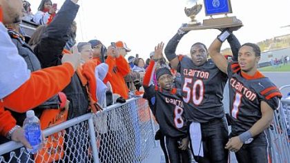 Clairton teammates (left to right) Vinny Moody, Devonte Harvey and Tyus Booker hold up their trophy after their team's win against Dunmore in the PIAA Class A championship Friday at Hersheypark Stadium in Hershey, Pa.