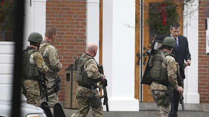 A Conn. State Police tactical team searches the area around Saint Rose of Lima Catholic Church after a scare during services Sunday.