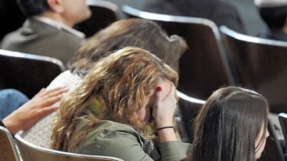 A woman covers her face at Sunday's interfaith memorial service as President Obama reads out the names of the 20 children killed at Sandy Hook Elementary School.
