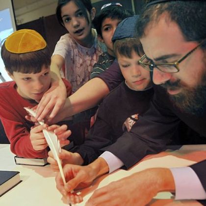 Joshua Sakolsky, 7, of Mt. Lebanon, second from right, whose name was chosen in a lottery, has the honor Sunday of filling in the first letter of a new Torah scroll at Beth El Synagogue in the South Hills.  With him are his brothers and sister, Aaron Sakolsky, 9, left; Brittany Shniper, 11, second from  left, and Robert Shniper, 12, center. Scribe Levi Selwyn, right, helps in filling in the first letter, "bet."