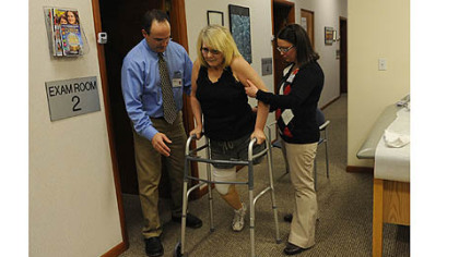 Double amputee Catherine Fielding  practices  walking as physical therapist Joseph Witt, left, and physical therapy assistant Darcy Skrip help during a physical therapy session.