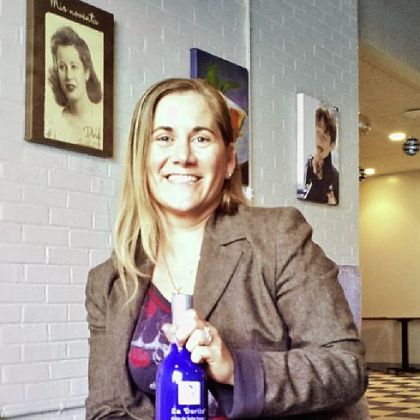 Josephine Oria, holding a bottle of "La Dorita" dulce de leche cream liqueur, in the company's new offices in Sharpsburg. In the upper left is a portrait of Maria Dora Germain, Ms. Oria's grandmother, who lives in Argentina and whose visage adorns the bottle.