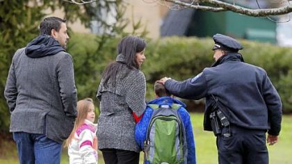 Easton, Conn., police officer J. Sollazzo greets a returning student Tuesday as he is walked into Hawley School in Newtown.
