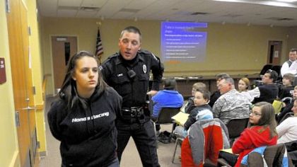 Cheyenne Sutton, 16, a Knoch High school student, and Edward Lenz, an Adams police officer, act out an arrest scene during a presentation of "Reality Tour "at the Adams municipal building. The dramatization of a life -- and death -- on drugs is presented monthly.
