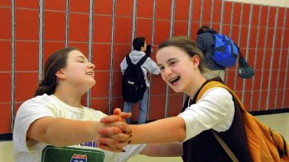 Eighth-graders Caroline Poeggel and Beth Fleming laugh as they dance through their new band room in the renovated middle school.
