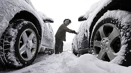 Noah Nichols of Des Moines, Iowa, cleans snow from his car early Thursday. The first widespread snowstorm of the season began a slow crawl across the Midwest with some areas receiving as much as 15 inches.