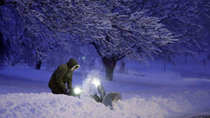 A resident clears snow from his driveway after an overnight snowfall left many schools and businesses closed for the day Thursday in Urbandale, Iowa.