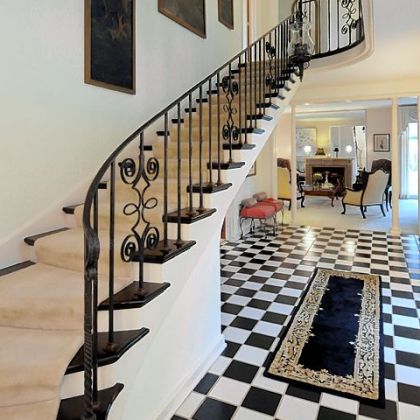 The foyer has a black-and-white checkerboard tile floor and winding staircase.