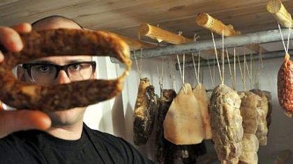 Chef Justin Severino examines a lamb sausage that has been curing in a temperature-controlled room at Cure.