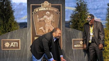 Franco Harris demonstrates his Immaculate Reception grab as John "Frenchy" Fuqua looks on during the unveiling Saturday of a historical marker on West General Robinson Street on the North Shore that designates the exact spot where the play occurred.