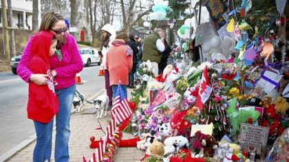 Deborah Gibelli holds her daughter, Alexandra, 9, on Monday, as they look at a memorial for those killed in the school shooting at Sandy Hook Elementary School in Newtown, Conn.