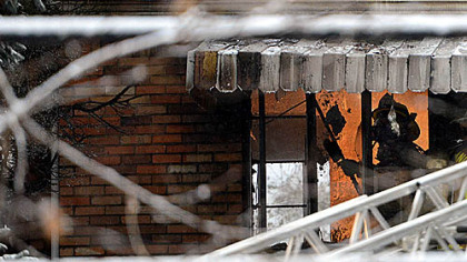 A firefighter works to enter the house this morning.