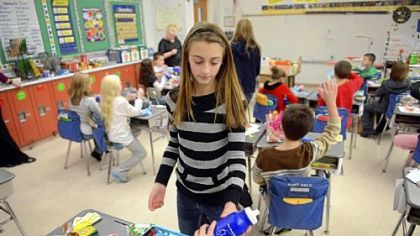 Kaylie Payne, 11, hands out reusable water bottles to a classroom as sixth-graders at South Allegheny Elementary School participate in Project Polar Bear on Friday.  The project advocates the reusable bottles instead of throwaway plastic bottles.