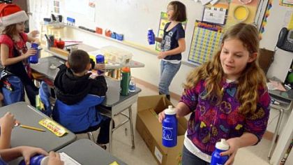 Hayden Bayura, right, 11, hands out reusable water bottles to a classroom.