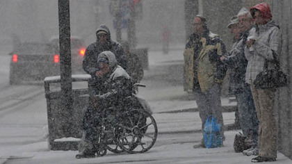 A group of people wait to cross Stanwix Street in Downtown Pittsburgh this morning as heavy snowfall continues.