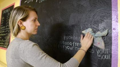 Danielle Green, 23, of Lawrenceville, cleans the menu boards Dec. 18 at the new Braddock Community Cafe.