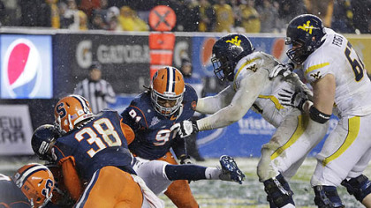 Syracuse defenders bring down West Virginia quarterback Geno Smith for a safety in the first half of the Pinstripe Bowl at Yankee Stadium in New York.