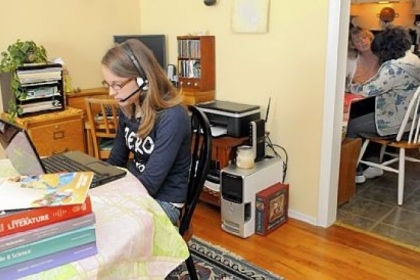 In June, PA Cyber school student Christina Buffalini, 15, works on her eighth-grade science in the family's dining room while her mother Jill Buffalini and sister Maria, 10, work in the kitchen.