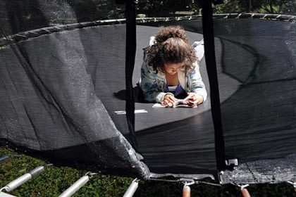 Maria Buffalini, 10, has a break between her cyber classes and uses the time to read a book on the family's trampoline in the back yard of their Franklin Park home.